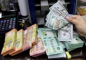 FILE PHOTO: A man counts U.S. dollar banknotes next to Lebanese pounds at a currency exchange shop in Beirut